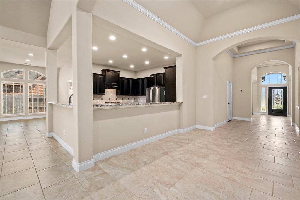 The open-concept layout offers uninterrupted views from the kitchen through to the entry, showcasing the home’s expansive design. Arched doorways and crown molding enhance the airy and connected feel throughout.
