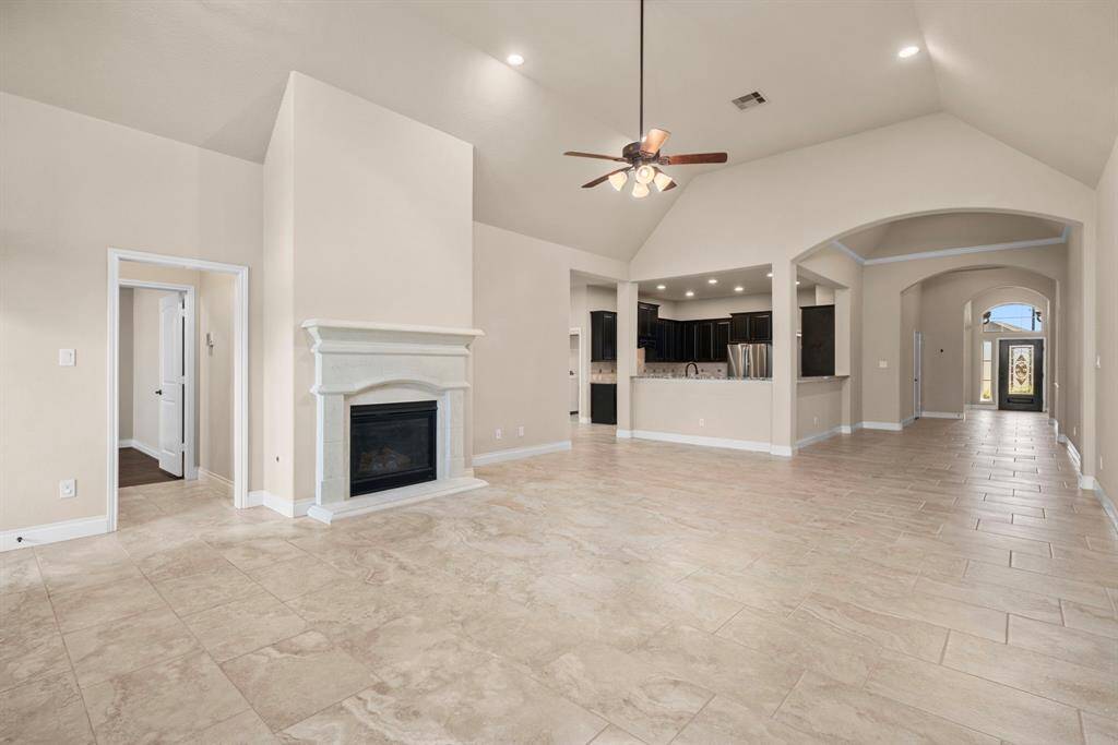 A spacious living area anchors the heart of the home, complete with high ceilings and tile flooring. The cozy gas fireplace adds a warm focal point, perfect for relaxing evenings at home.