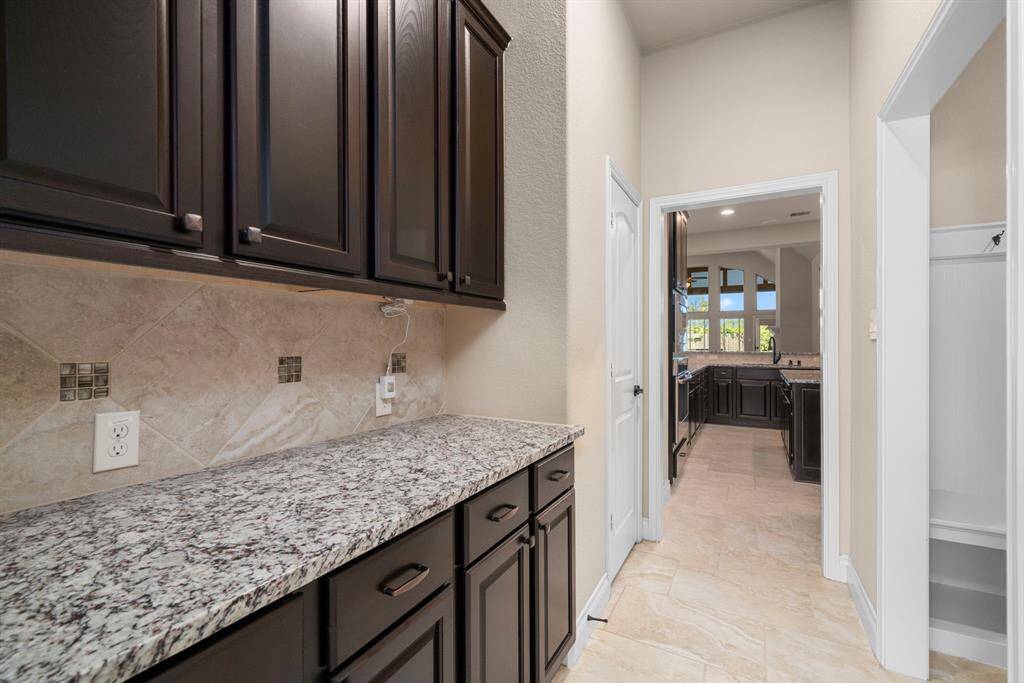 A granite-topped butler’s pantry sits just off the kitchen, providing extra prep space and additional storage. It’s the perfect setup for coffee service, staging meals, or housing small appliances.