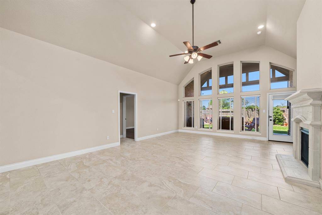 Tall vaulted ceilings and a full wall of windows fill the living room with natural light and serene backyard views. The neutral tones and spacious layout make this room the perfect backdrop for any style.