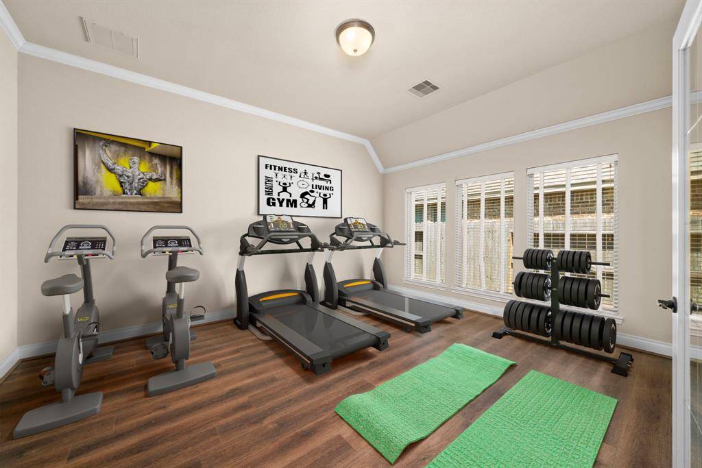 From this view, the flex room flows seamlessly into the kitchen through double glass doors. Crown molding and warm-toned, wood-look flooring give the room a polished, professional feel. *Virtual Staged*