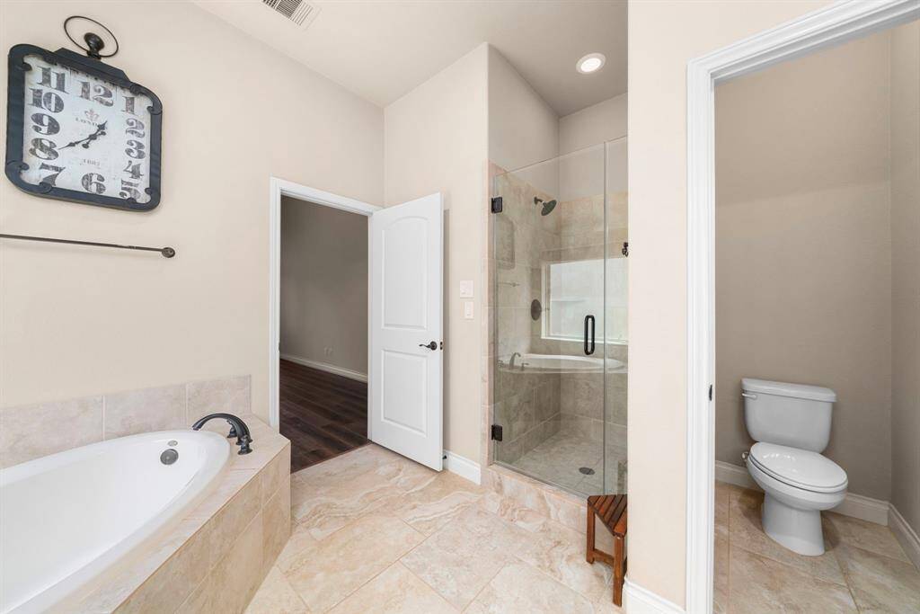 From this angle, you’ll appreciate the spacious walk-in shower with glass enclosure and bronze fixtures. The private water closet and entry to the bedroom enhance the functionality of this luxurious suite.