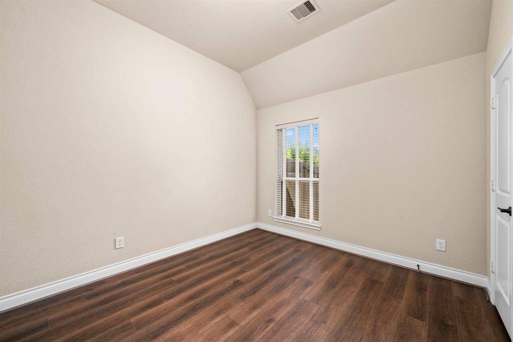 This secondary bedroom features recently installed luxury vinyl plank flooring and a bright window for a comfortable and private retreat. High ceilings and a neutral color palette provide a welcoming atmosphere.