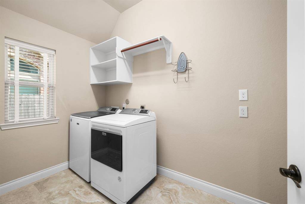 This bright and functional laundry room off of breakfast room features tile flooring and a large window that brings in natural light.