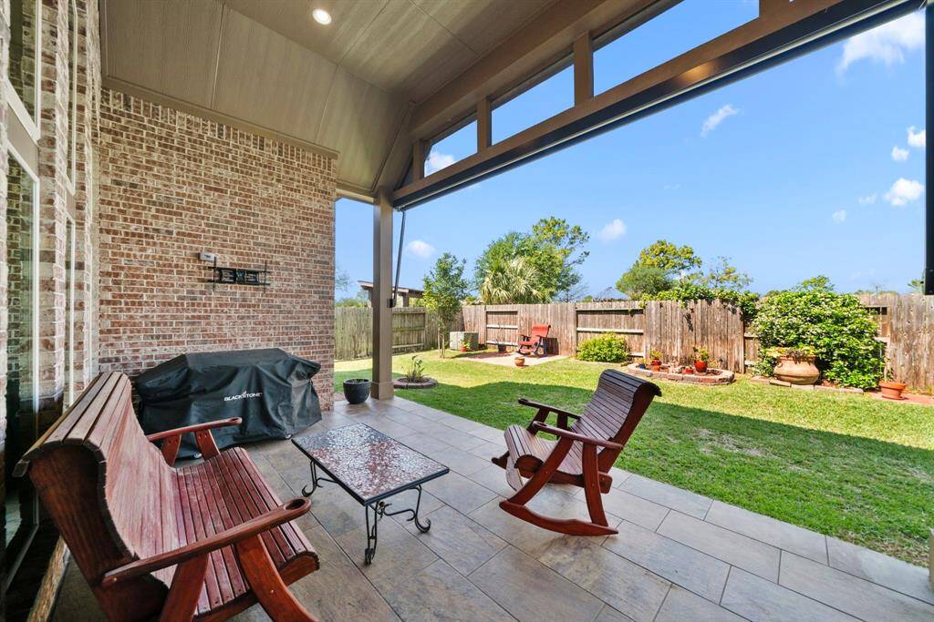 Relax under the shade while overlooking the beautifully maintained backyard with potted plants and garden beds. The covered area is ideal for outdoor dining or simply enjoying the fresh air.