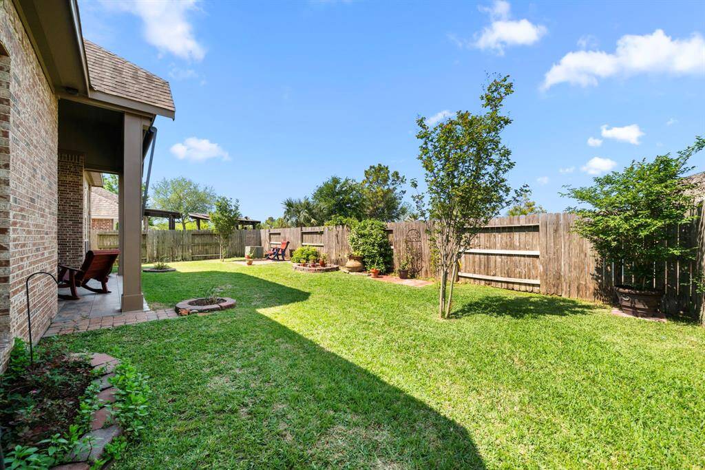 The backyard is a gardener’s dream with curated landscaping, pavers, and planting areas. Mature trees and shrubbery provide beauty, while the open lawn offers space for outdoor fun.