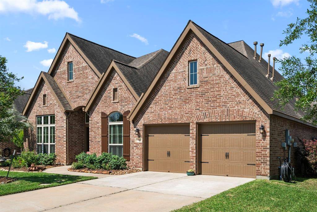 A closer look reveals thoughtful architectural details, fresh exterior paint (2024), and a brick façade that enhances the timeless charm of the home. The double-wide driveway and tandem 3-car garage with epoxy floors offer ample space for vehicles and storage.