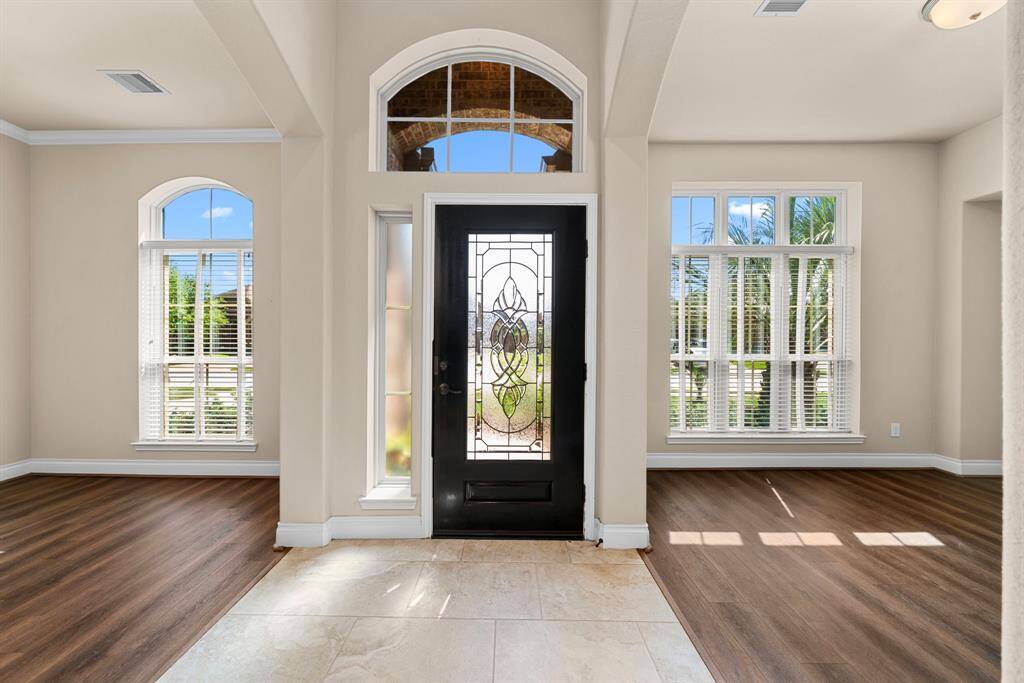 Step inside to a bright and welcoming foyer, accented by a beautifully detailed front door and soaring ceilings. Natural light pours through the large windows, creating a cheerful ambiance from the moment you enter.