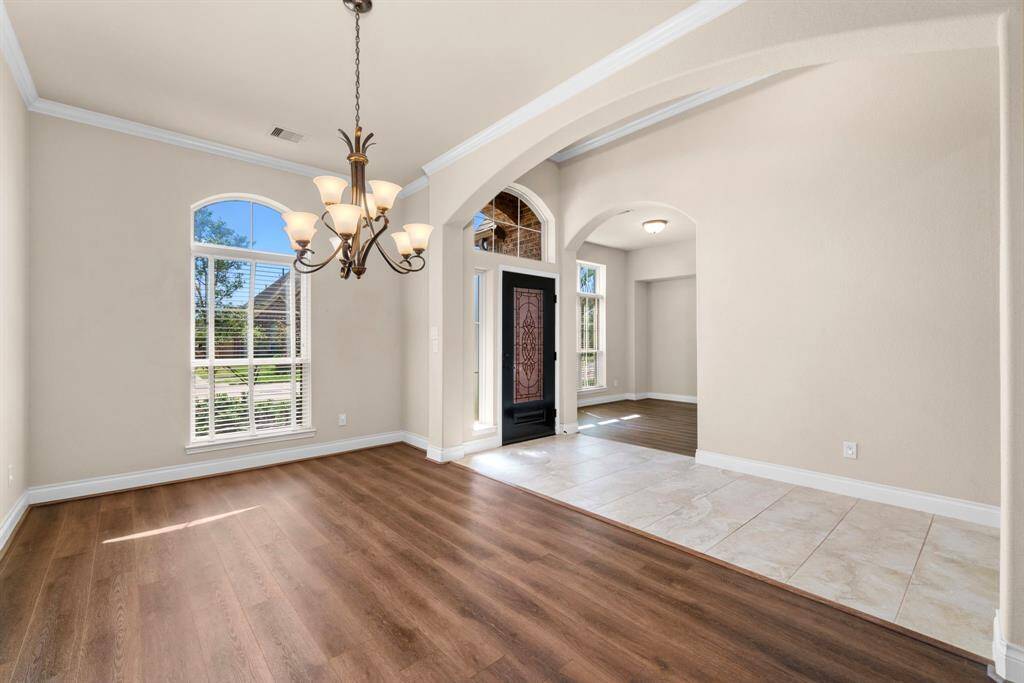 The formal dining area sits just off the entry, framed by elegant archways and crown molding. Recently installed LVP flooring (2022) adds warmth and durability, ready for gatherings and celebrations.