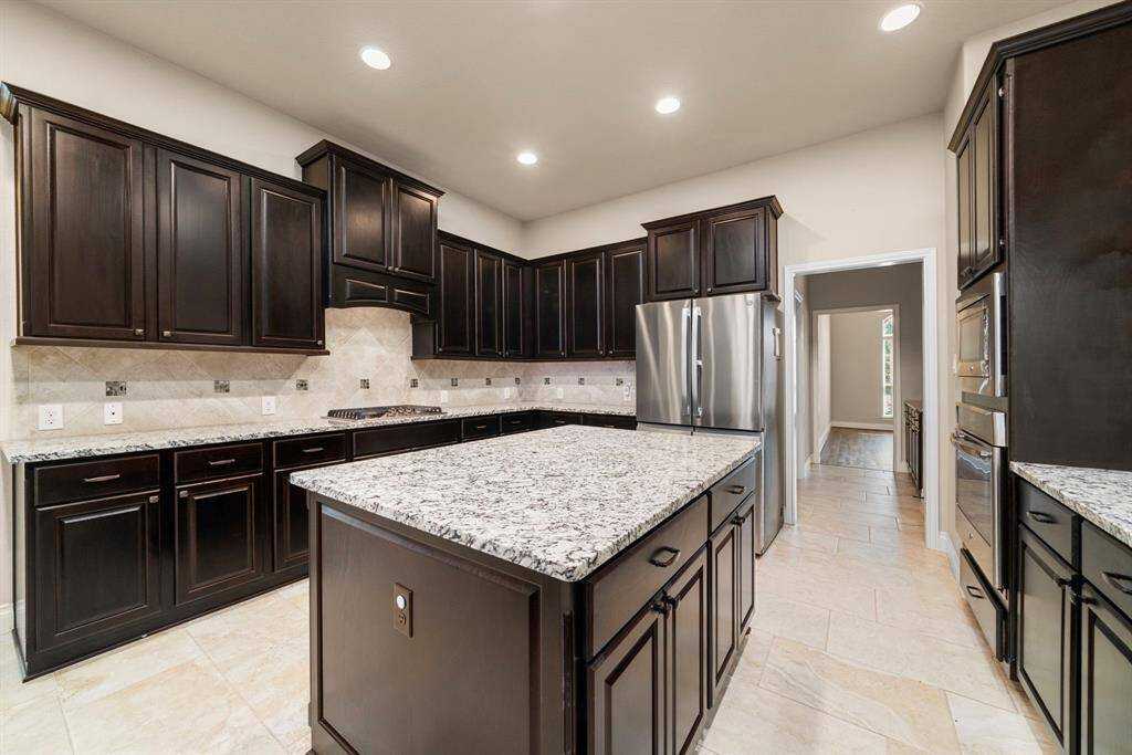 From this angle, the kitchen’s extensive cabinetry and thoughtful layout are on full display, offering abundant storage. The combination of tile flooring and upscale finishes creates a clean, modern aesthetic.