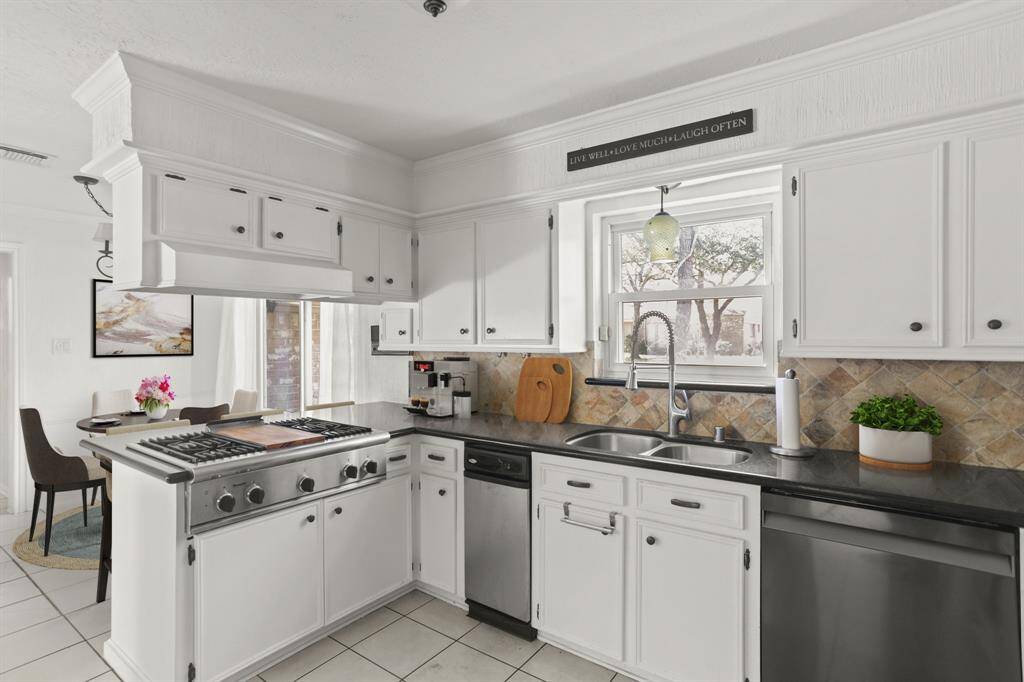 Virtually Staged: This wonderful kitchen features tile floors, granite countertops, white cabinets, a window, crown molding, and a gorgeous tile backsplash.