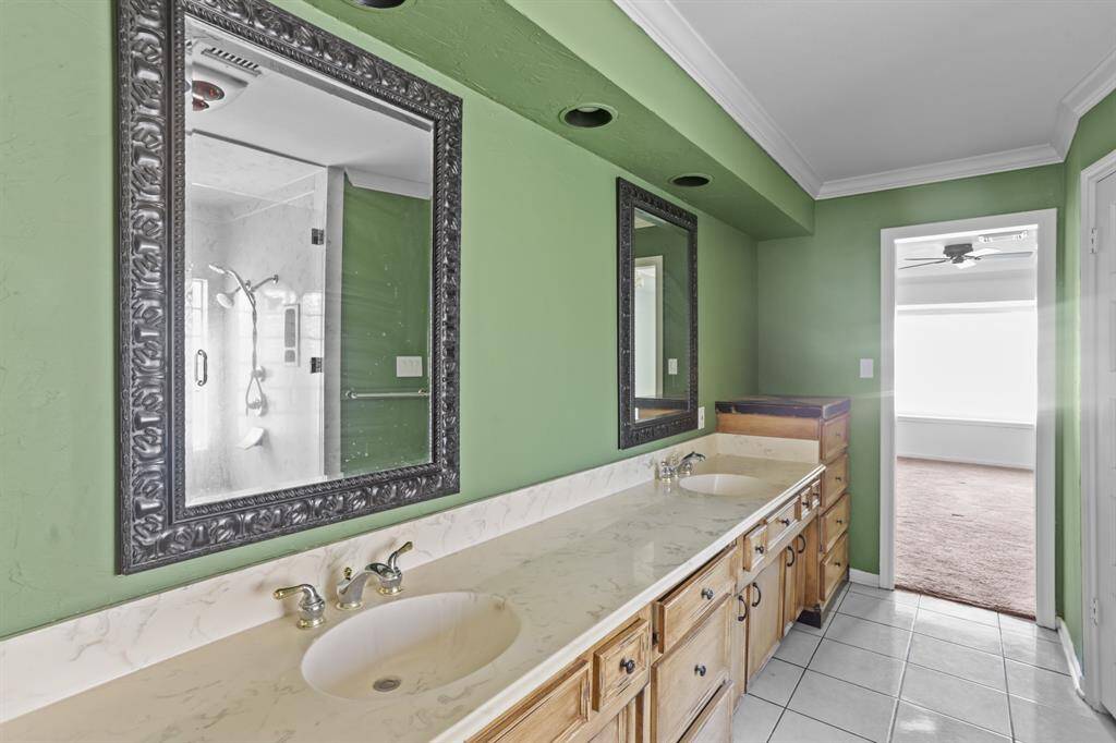 WOW! Spacious and beautifully appointed Primary Bathroom, featuring double sinks with framed mirrors, recessed lighting, tile floors, and beautiful wooden cabinets with granite countertops.