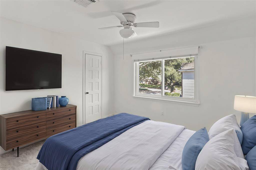 Virtually Staged: This lovely secondary bedroom features a neutral color, plush carpet, a large window, a ceiling fan, and a walk-in closet.