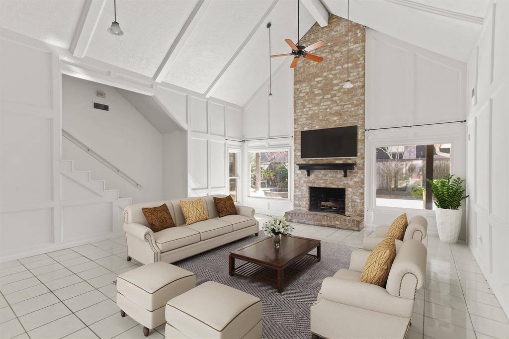 Virtually Staged: This living room is open and bright! Gorgeous brick fireplace accent wall, high ceilings, and large windows with beautiful view of the backyard.