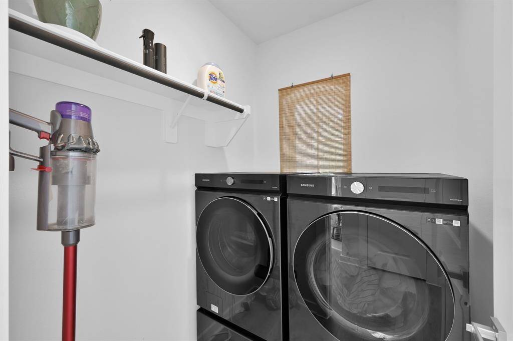 The laundry room is located off the entry way and features a window with custom blind and elevated front-load washing machine and dryer. These stay with the home, making move-in even easier!