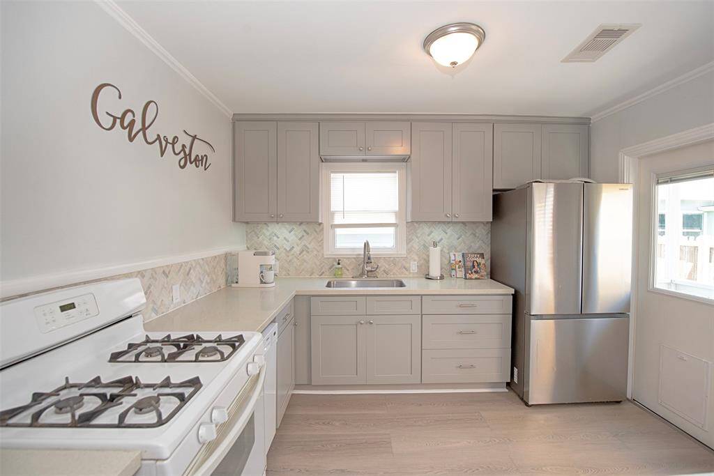 Amazing updated kitchen with shaker style cabinetry, gas range and newly updated porcelain tile floors. Kitchen also has beautiful quartz counters and motion activated under-cabinet lights!