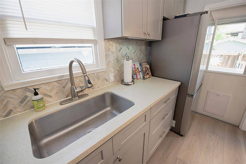 A closer look at the quartz counters with stunning marble tile back splash in a chevron pattern, and this awesome single bowl deep sink. The French door stainless fridge which will stay with the house as well.