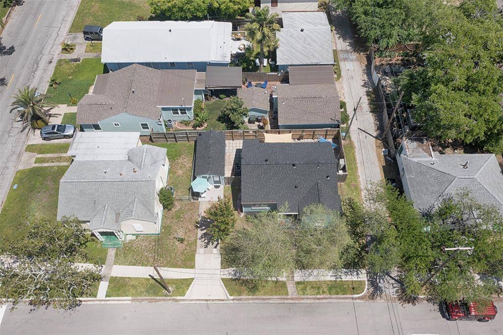An aerial view of the property shows the home and an adjacent studio which could be a rental unit or 3rd bedroom with 2nd bath as well as the backyard entertainment space. Home also has a new roof just installed in March 2025.