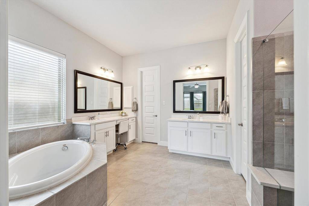 Primary Bathroom featuring dual vanities, soak in tub, and oversized shower