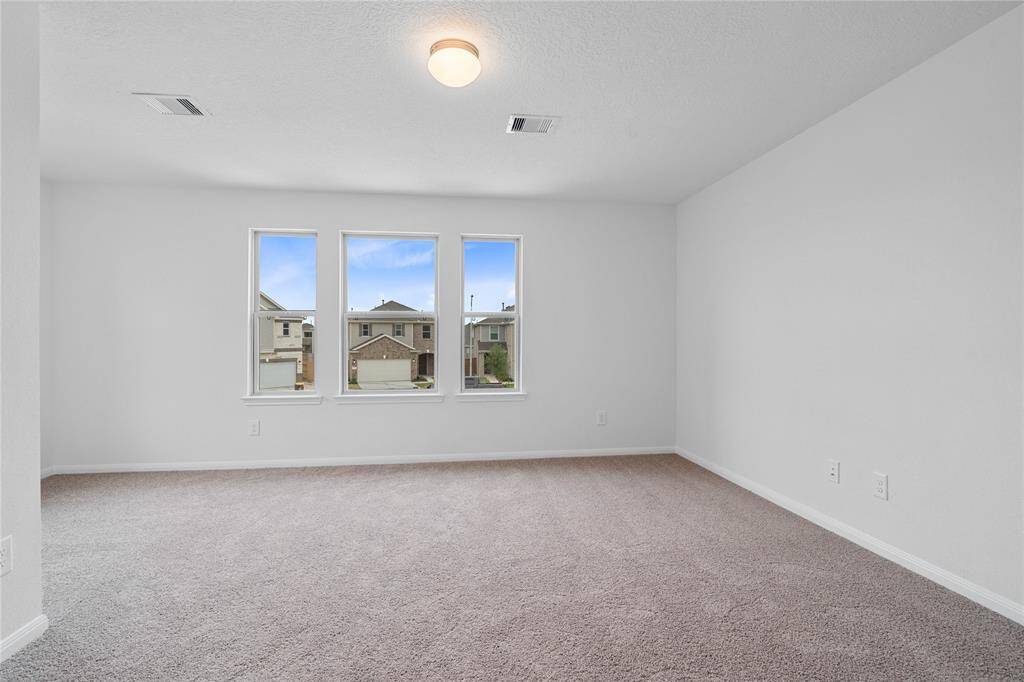 Come and unwind after a long day in this magnificent primary suite! This spacious room features plush carpet, warm paint, high ceilings, lighting, and large windows.