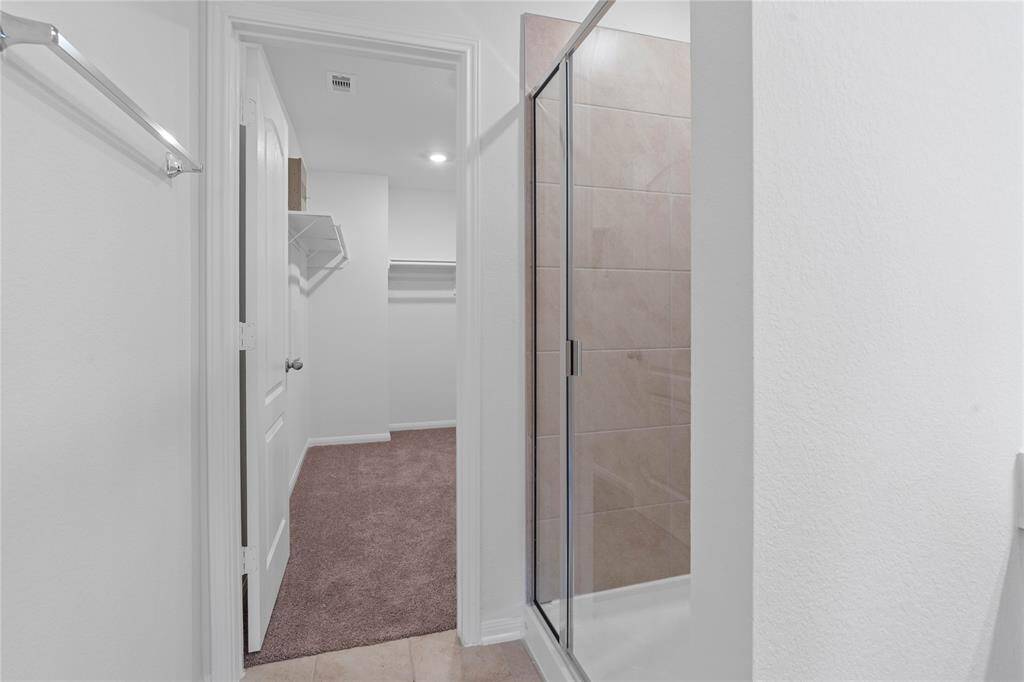 This additional view of the primary bath showcases the walk-in shower with tile surround and walk-in closet.