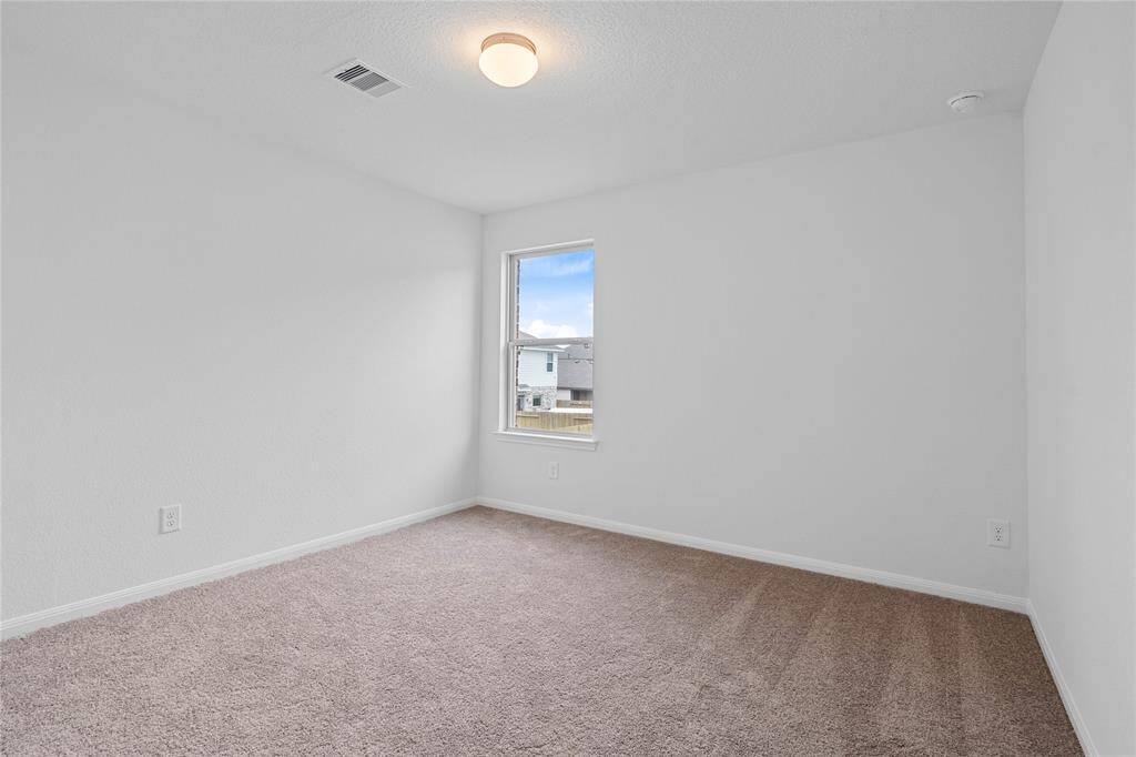 Secondary bedroom features plush carpet, custom paint, closet space, lighting, and a large window.
