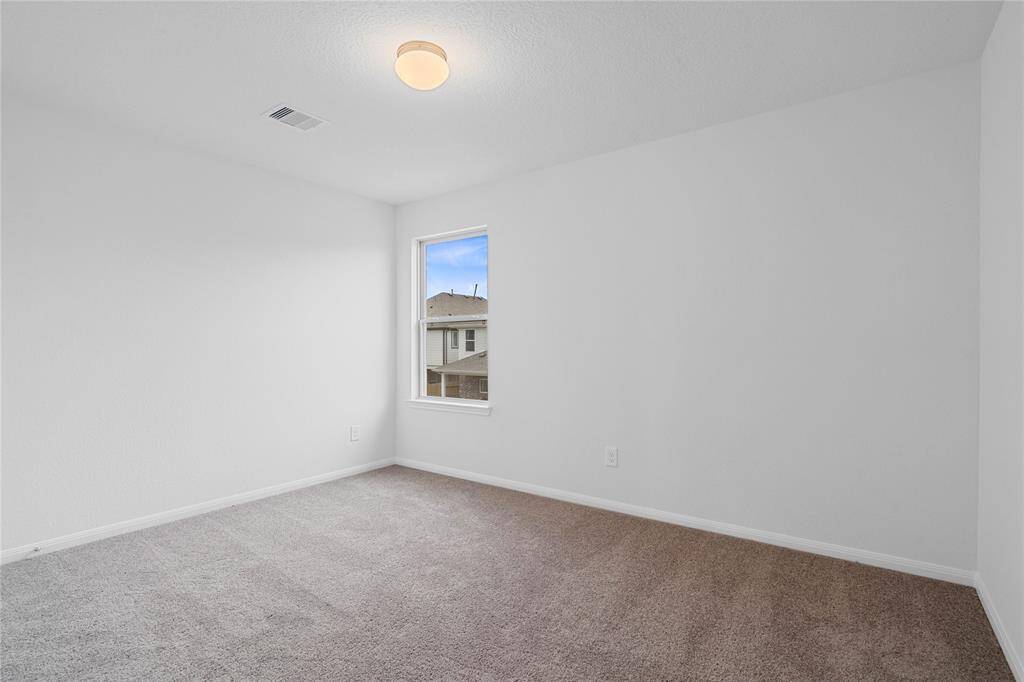 Secondary bedroom features plush carpet, custom paint, closet space, lighting, and a large window.