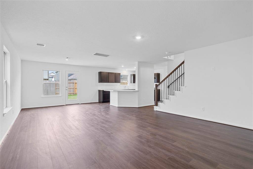 The open concept great room, dining and kitchen makes for a impressive way to keep the party going and never miss a beat! The Great Room features large windows, high ceilings, recessed lighting, wrought iron stair rails on staircase, and Bandera Vinyl Plank flooring!