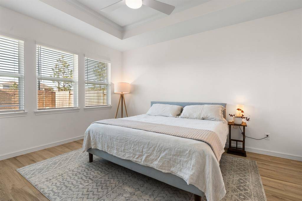 Primary bedroom is bright and spacious, with space for a large bed, wood look tile floors.