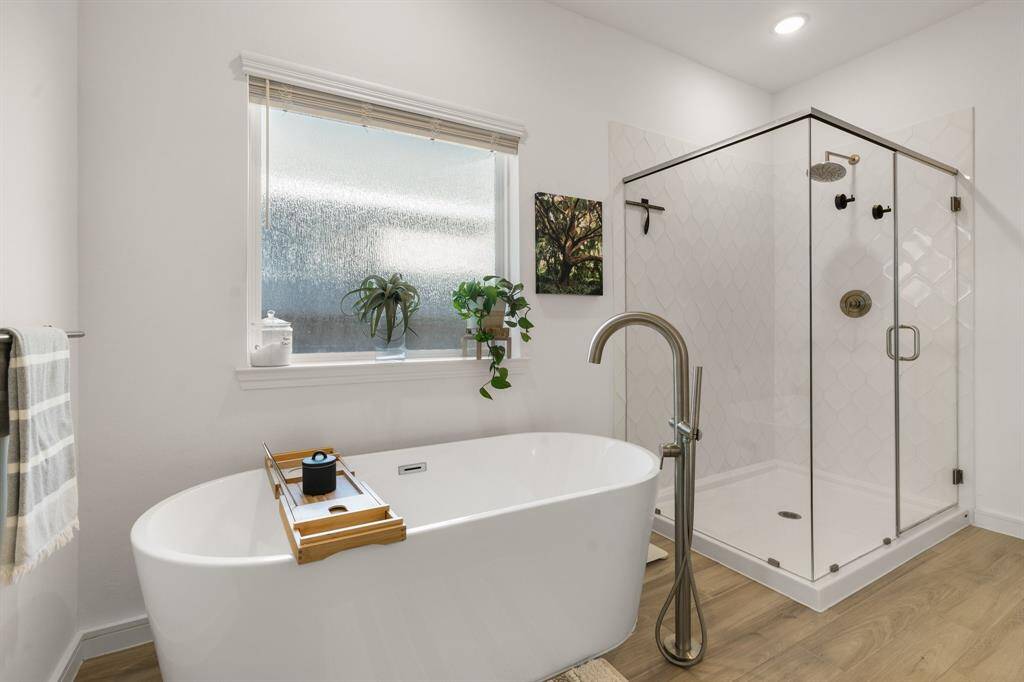 Luxurious soaking tub paired with an elegant standalone shower and large window for natural light.