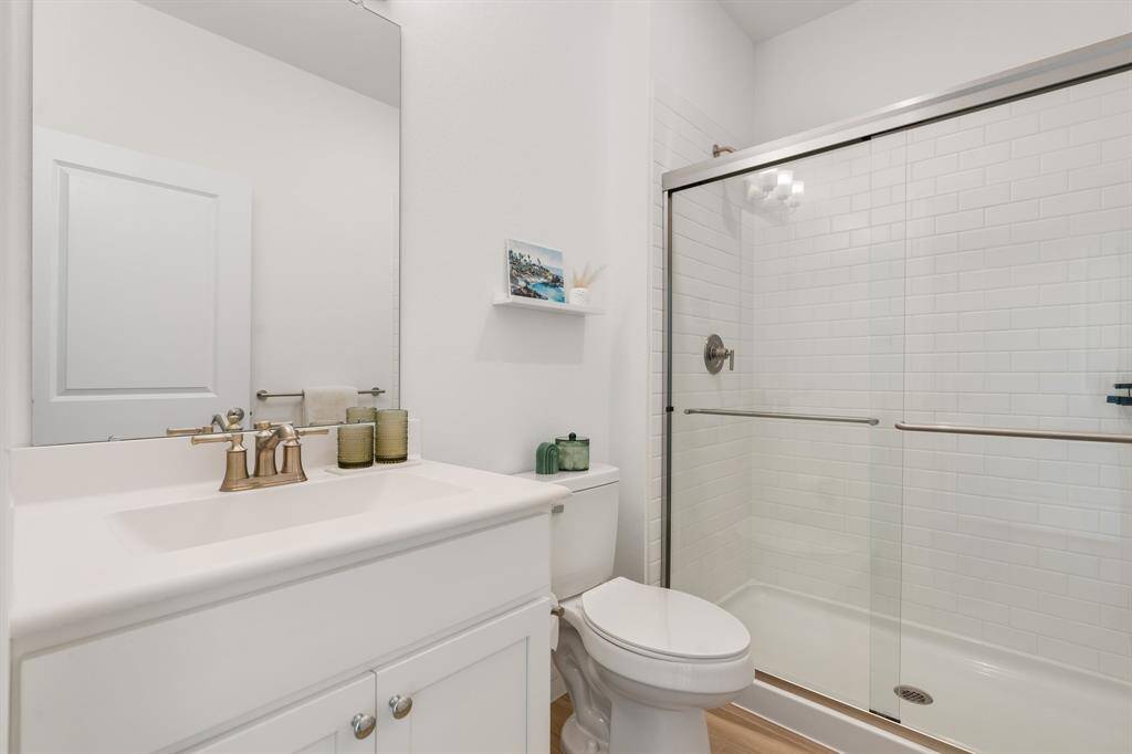 This bathroom features a clean, modern design with a white vanity and sink, a glass-enclosed shower.