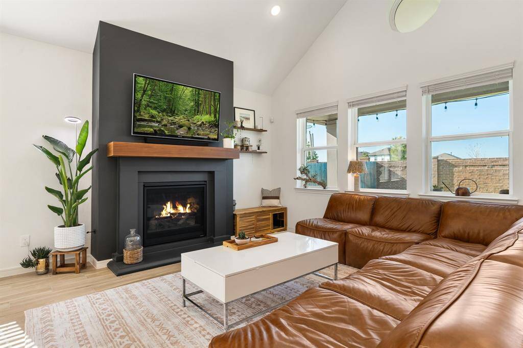 Experience cozy elegance in this sunlit living area, featuring a custom fireplace with a mango wood mantle as its stunning centerpiece.