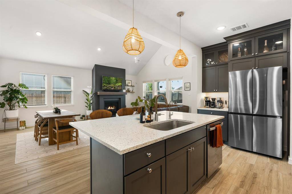 This open-concept kitchen and living area has great natural light from multiple windows, and includes a cozy fireplace and dining area.