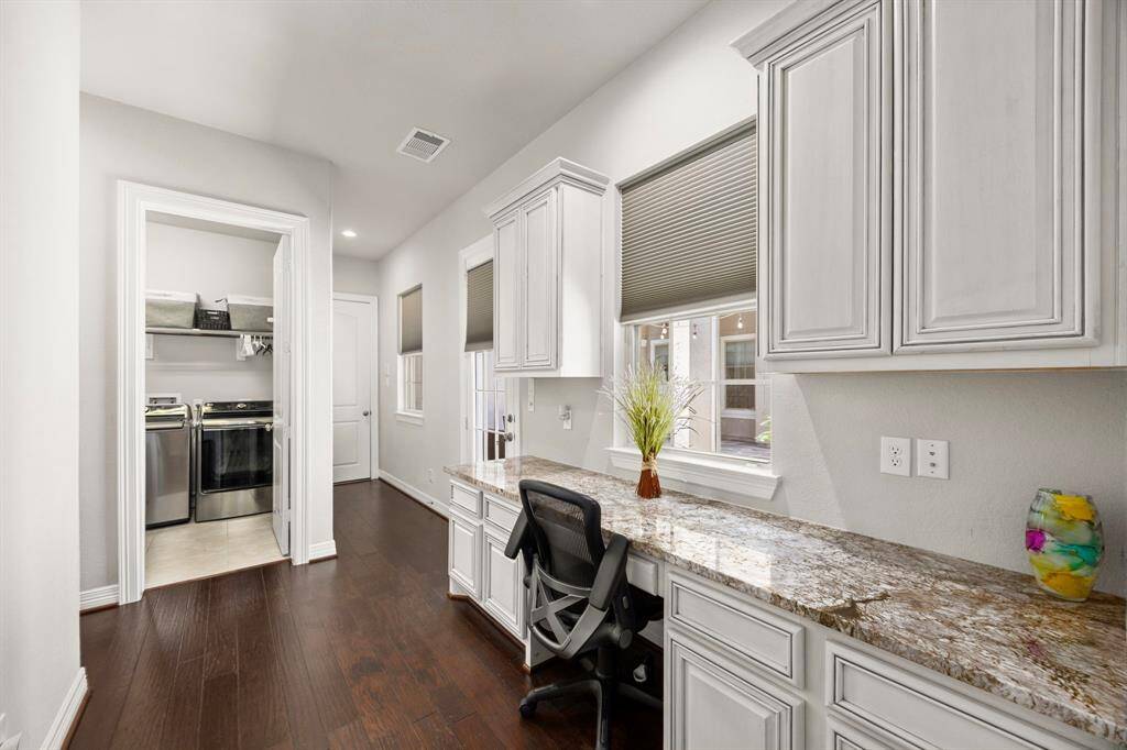 This extra back foyer area is located in the hallway leading to the utility room an both garage entrances. The desk area overlooks the front courtyard and could be a perfect place for homework, searching recipes, or folding clothes. The door at the end of the counterspace and all those extra cabinets, will take you out to the courtyard.