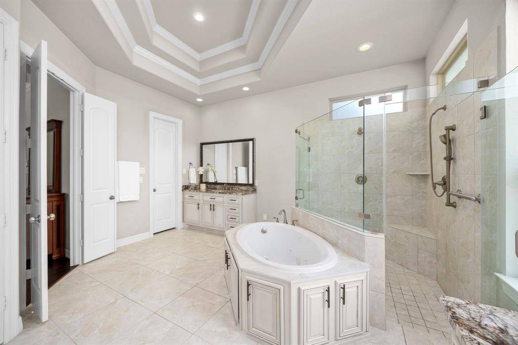 The handsome ensuite primary bathroom resembles private spa.  With a high tray ceiling, a luxurious double shower and soaking tub, you will want to stay all day.