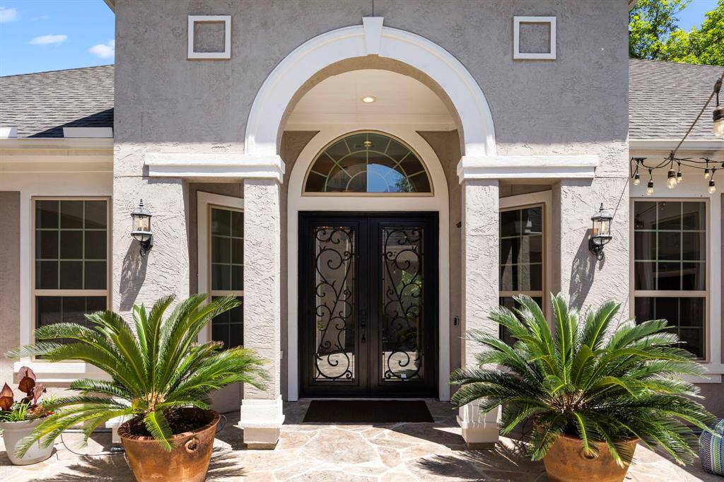 From the courtyard, a covered archway flanked with side columns and plantersare inviting you inside to this amazing property.