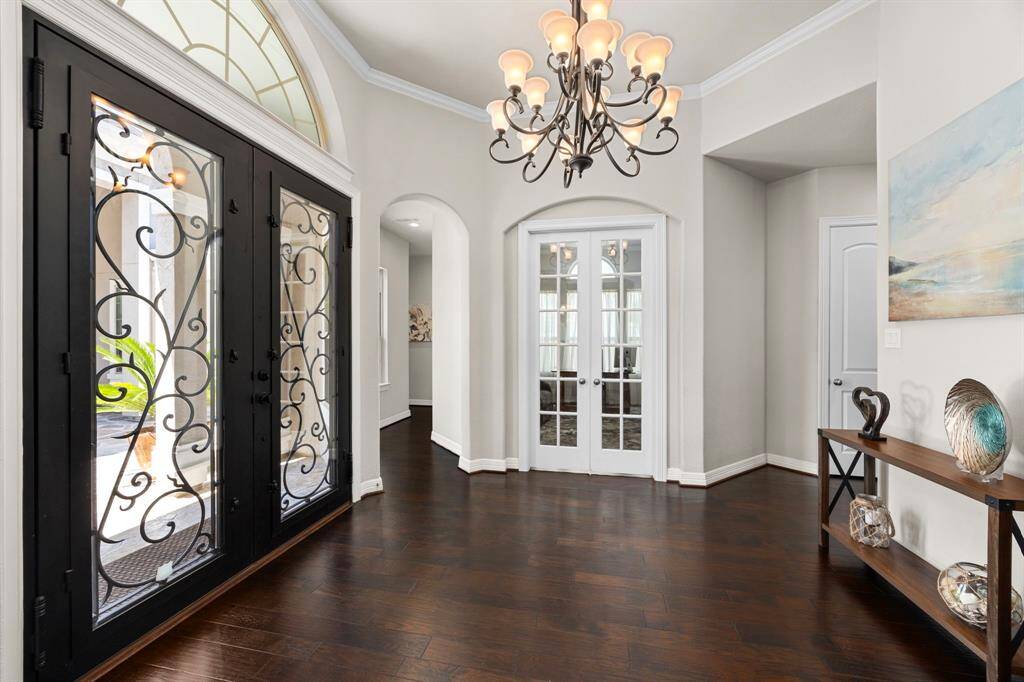 Welcome! Upon stepping inside the handsome, iron accented double front doors with a transome window, you are greeted with soaring, tiered ceilings, expansive hardwood flooring, and graceful archways that perfectly delineate rooms in this fabulous open concept home.