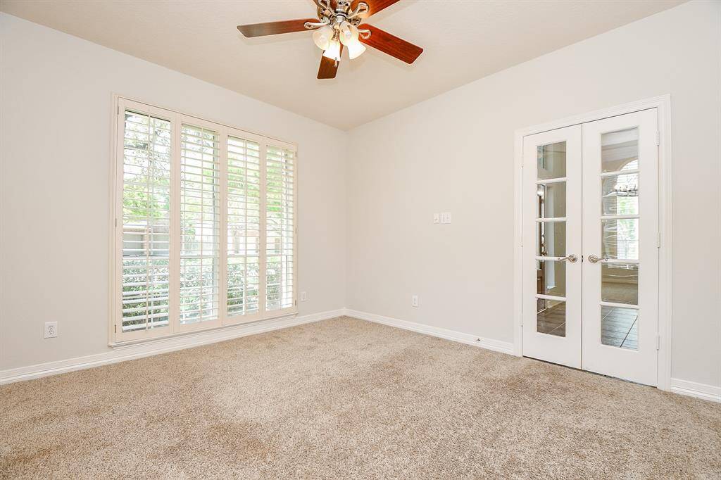 Bright and inviting study with large windows, elegant French doors, and cozy carpet, perfect for productivity and relaxation.