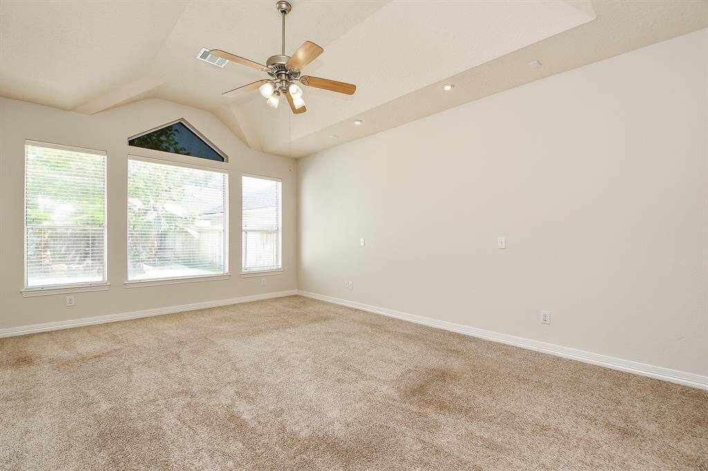 Spacious and bright primary bedroom featuring high ceilings, elegant recessed lighting, and large windows for abundant natural light.