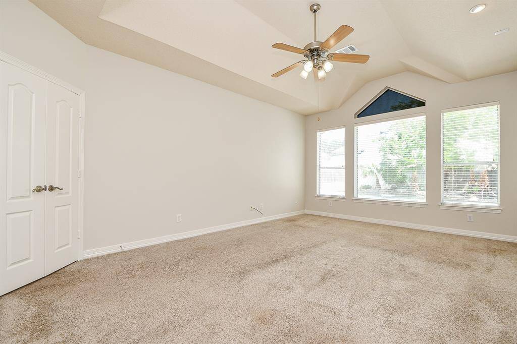 Spacious primary bedroom featuring vaulted ceilings, abundant natural light, and plush carpeting for ultimate comfort.