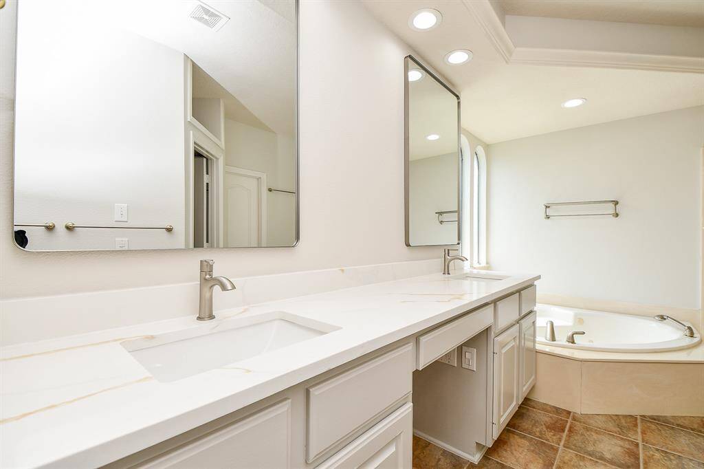 Luxurious primary bath featuring dual vanities, elegant fixtures, and a relaxing soaking tub.