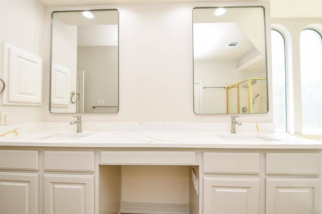 Luxurious primary bath featuring dual sinks, elegant mirrors, and abundant natural light.