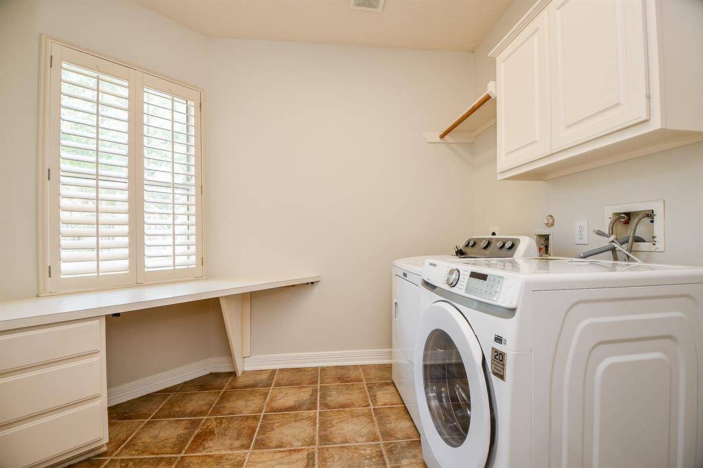 Spacious laundry room with ample storage, countertop workspace, and natural light streaming through elegant shutters.