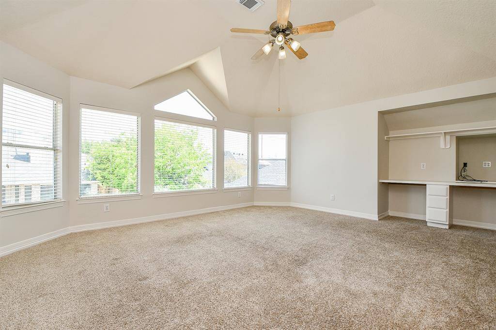 Spacious and bright game room with plush carpeting, abundant natural light, and a convenient built-in desk area.