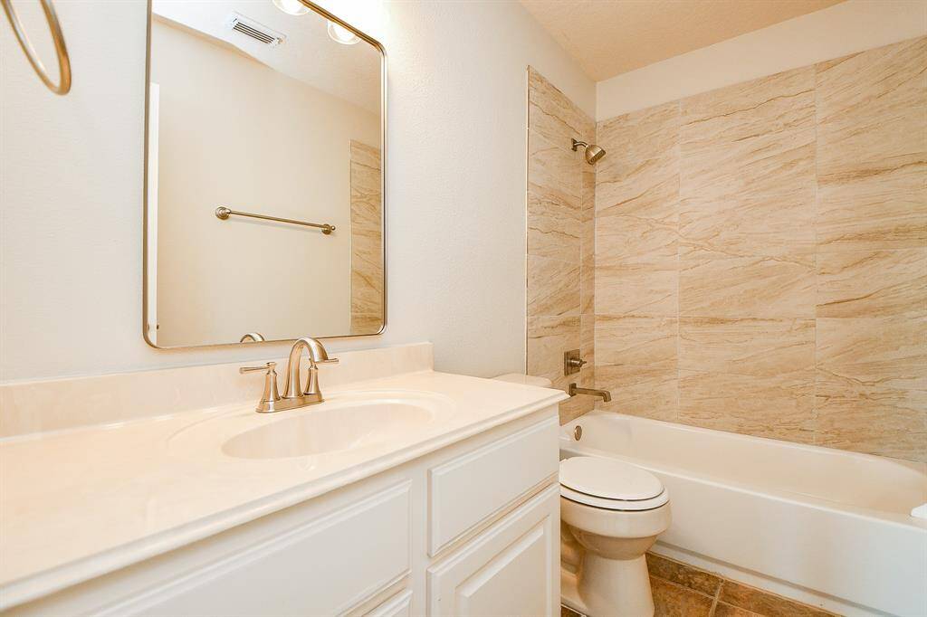Elegant secondary bathroom featuring a sleek vanity, modern fixtures, and a stylishly tiled shower.