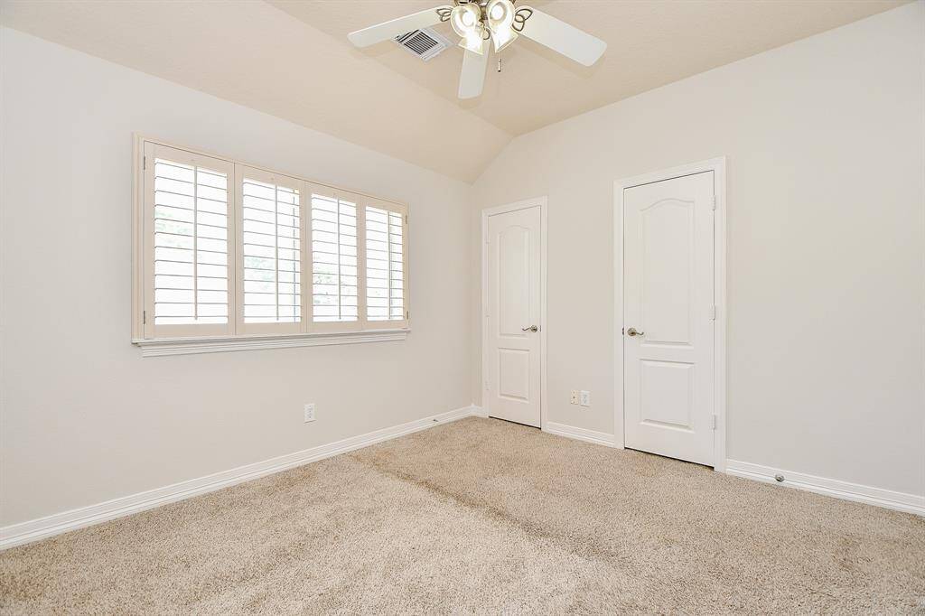 Cozy and bright secondary bedroom featuring elegant plantation shutters for a serene atmosphere.