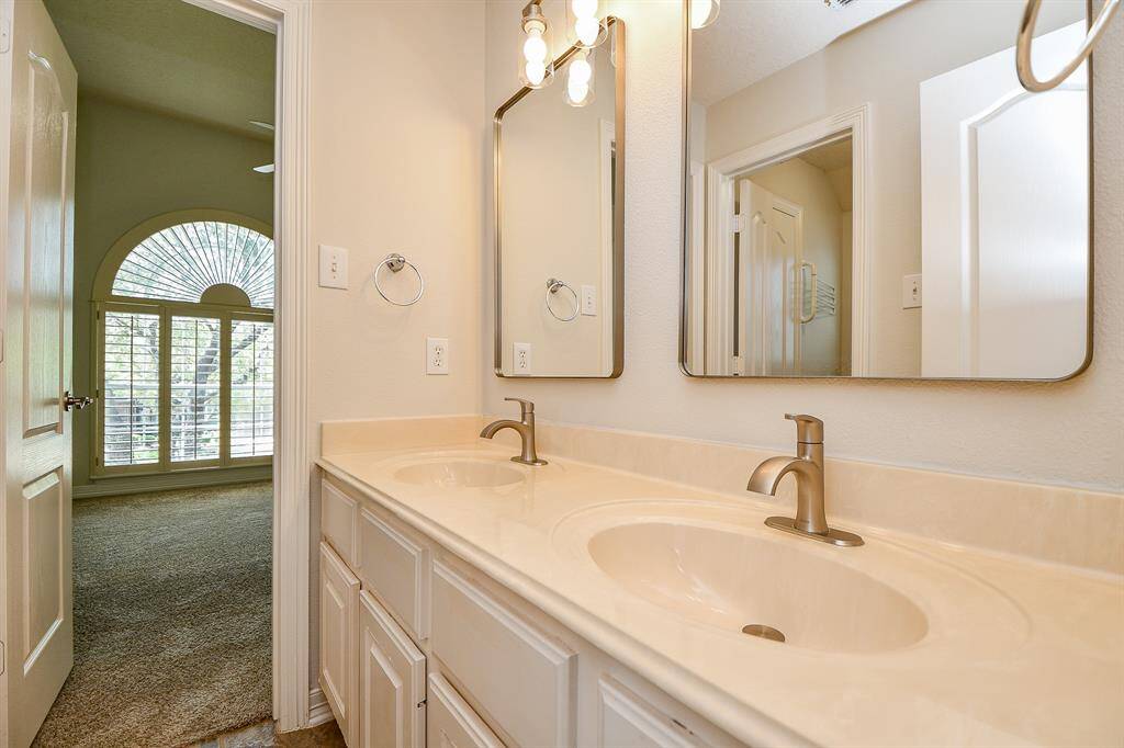 Bright and spacious secondary bathroom featuring dual sinks and elegant fixtures, perfect for family or guests.