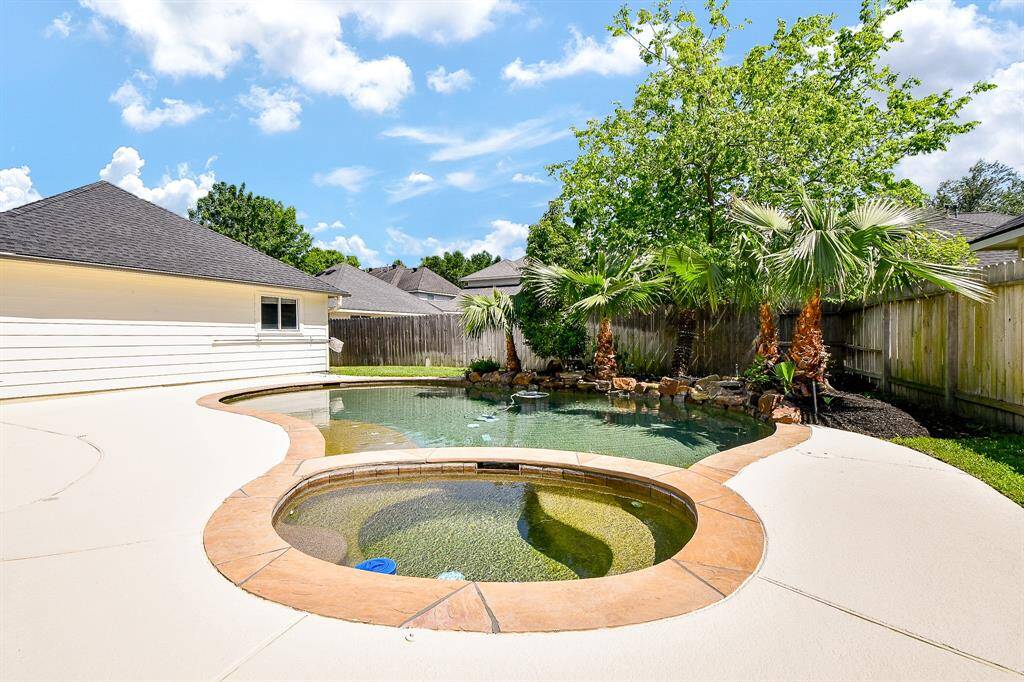 This backyard features a beautiful pool with a spa, surrounded by lush greenery and palm trees, offering a private oasis for relaxation and entertainment.