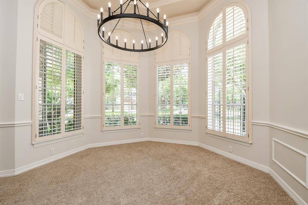 Elegant dining room with tall arched windows, abundant natural light, and a striking chandelier.