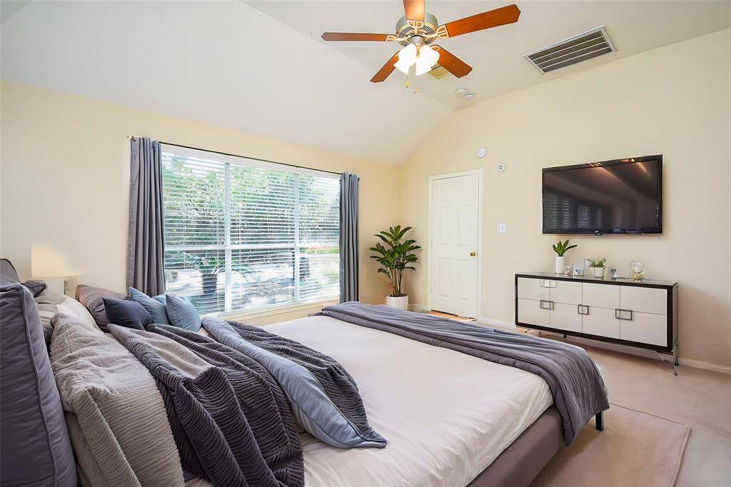 The spacious primary bedroom features large windows that fill the room with natural light and offer a peaceful view of the backyard, creating a serene and relaxing retreat. Virtually staged photo